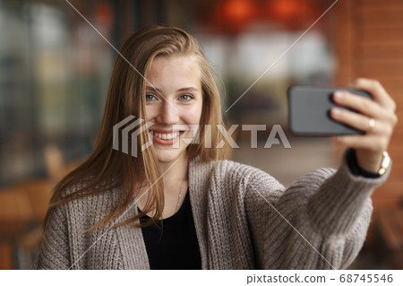 Young woman with shopping bag looking at phone on sunny autumn day. 68745546
