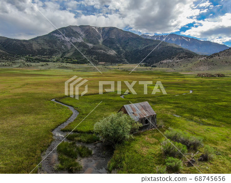 Aerial view of abandoned little wooden house barn next small river in the green valley, Aspen Spring Aerial view of abandoned little wooden house barn next small river in the green valley, Aspen Spring 68745656