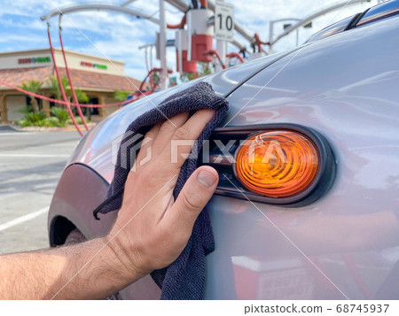 Man's hand cleaning the car with black microfiber cloth. Hand wipe down surface of car Man's hand cleaning the car with black microfiber cloth. Hand wipe down surface of car 68745937