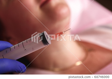 Cosmetologist injecting ozone to chin. Patient is sitting in chair with closed eyes. This therapy is purposed to increase oxygen in a body. Cosmetologist injecting ozone to chin. Patient is sitting in chair with closed eyes. This therapy is purposed to increase oxygen in a body. 68746000