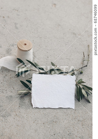 Summer wedding stationery mock-up scene. Blank business, place card. White silk georgette ribbon, olive branches and fruit. Grunge concrete background. Vertical feminine flat lay, top view. Summer wedding stationery mock-up scene. Blank business, place card. White silk georgette ribbon, olive branches and fruit. Grunge concrete background. Vertical feminine flat lay, top view. 68746099