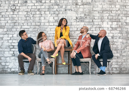 Beautiful cheerful professional woman wearing eyeglasses seated with male co-workers and team leader at work Beautiful cheerful professional woman wearing eyeglasses seated with male co-workers and team leader at work 68746266