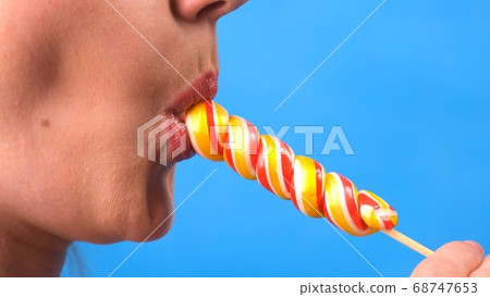 sexy brunette woman with lollipop isolated on a blue background. 68747653