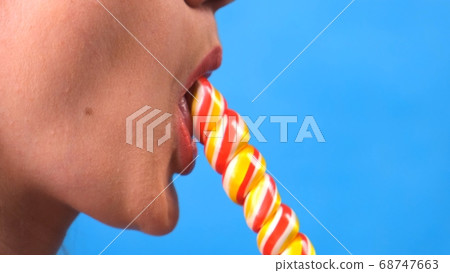sexy brunette woman with lollipop isolated on a blue background. 68747663