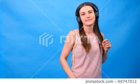 Beautiful Energy Girl with headphones listening to music on a blue background in the studio 68747812