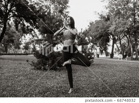 Woman doing yoga in the park. Concentration and energy of nature. Woman doing yoga in the park. Concentration and energy of nature. 68748032