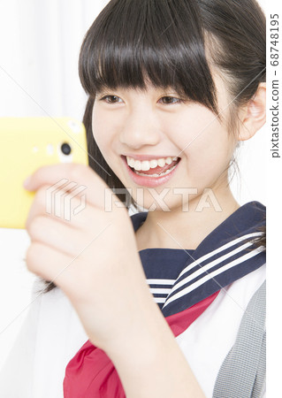 Female junior high school student looking at smartphone 68748195