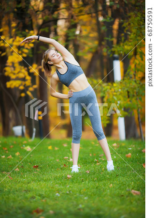 Woman Listening Music On Phone While Exercising Outdoors 68750591