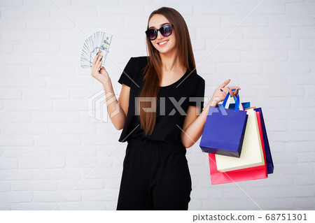 Shopping. Woman holding colored bags on light background in black friday holiday Shopping. Woman holding colored bags on light background in black friday holiday 68751301