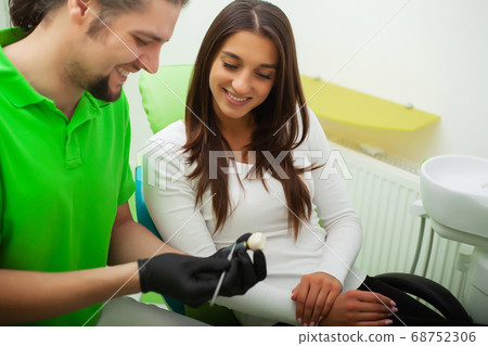 Dentist in dental office talking with female patient and preparing for treatment 68752306