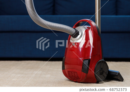 Red vacuum cleaner on a beige carpet 68752373