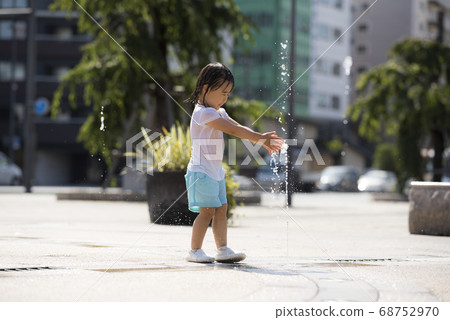Children playing in the fountain in the square 68752970