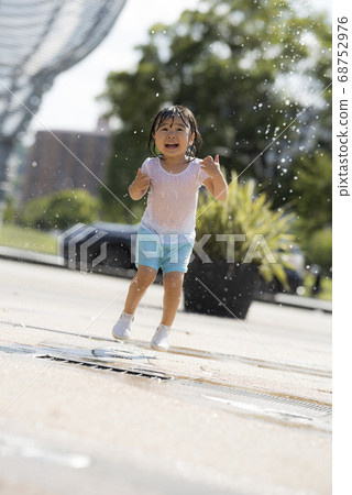 Children playing in the fountain in the square 68752976