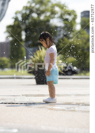 Children playing in the fountain in the square 68752977