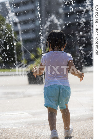 Children playing in the fountain in the square 68752978
