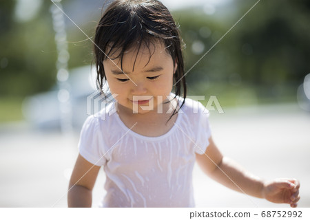 Children playing in the fountain in the square 68752992