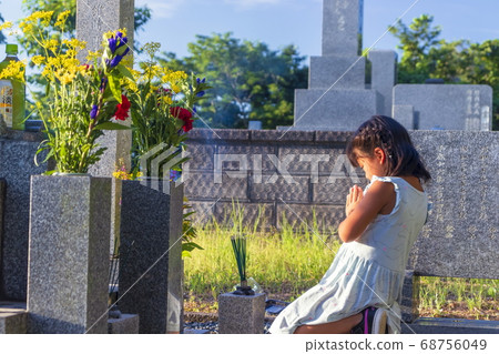 A visit to the grave A girl silently puts her hands together in front of the grave A visit to the grave A girl silently puts her hands together in front of the grave 68756049