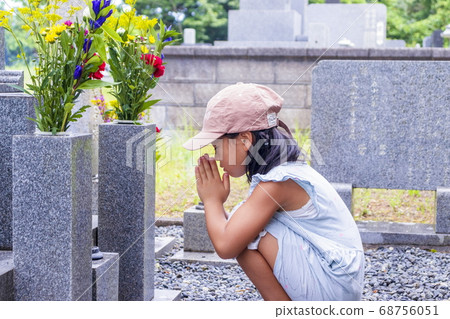 A visit to the grave A girl silently puts her hands together in front of the grave A visit to the grave A girl silently puts her hands together in front of the grave 68756051