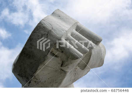large stone fist hand holding an antique sculpture against a blue sky large stone fist hand holding an antique sculpture against a blue sky 68756446