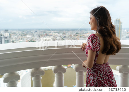 woman standing on the balcony and looking view of 68758610