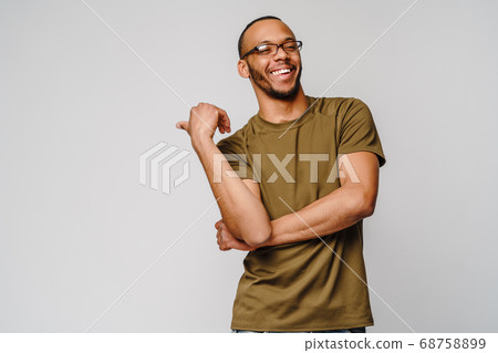 Joyful friendly african-american young man in green t-shirt pointing by finger at copy space Joyful friendly african-american young man in green t-shirt pointing by finger at copy space 68758899