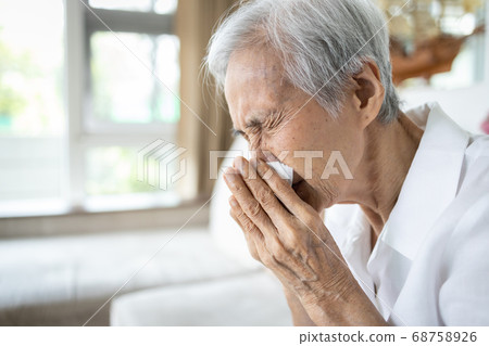 Sick asian senior woman blowing nose with tissue paper while runny nose,sneeze,elderly with sinusitis,sinus virus disease,infection symptom of flu,cold,fever,old people with respiratory problems 68758926