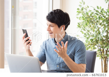 A man who makes a hands-free call on a smartphone during work 68761013