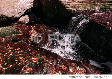 Beautiful waterfall with autumn leaves covered stones 68761452