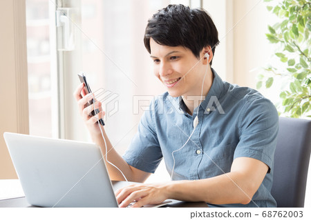 A man who makes earphone calls with a smartphone during work 68762003