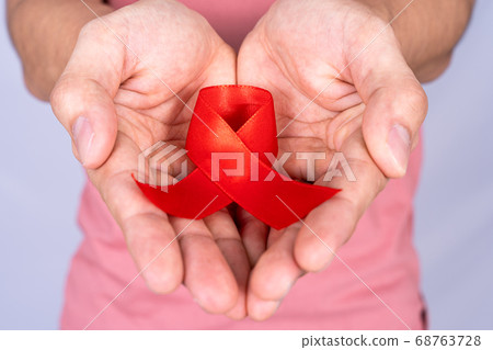 Red AIDS awareness ribbon holding by man on grey Red AIDS awareness ribbon holding by man on grey 68763728