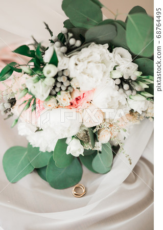 Beautiful toned picture with wedding rings against the background of a bouquet of flowers Beautiful toned picture with wedding rings against the background of a bouquet of flowers 68764495