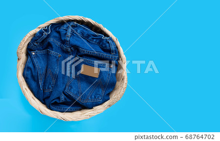 Jeans in laundry basket on blue background. Jeans in laundry basket on blue background. 68764702