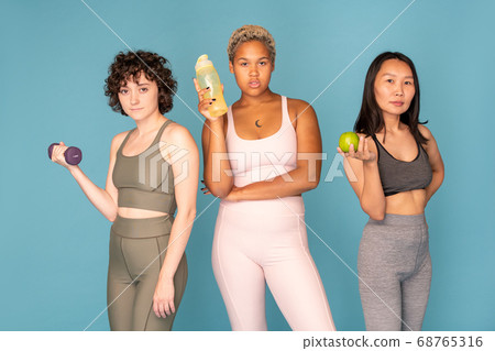 Three young pretty active females of various ethnicities wearing tracksuits Three young pretty active females of various ethnicities wearing tracksuits 68765316