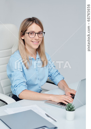 Young successful businesswoman in eyeglasses looking at you with toothy smile 68765656