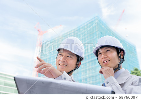 Businessman looking at drawings on construction site 68766097