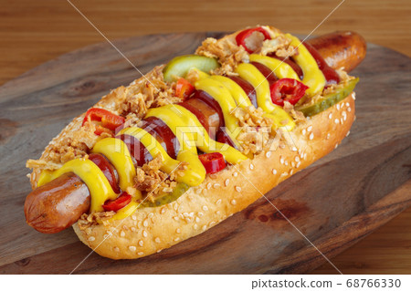 Hot dog with yellow mustard and ketchup on wooden board 68766330