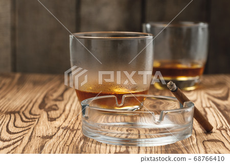 Two glasses of whiskey with an empty ashtray on wooden table Two glasses of whiskey with an empty ashtray on wooden table 68766410