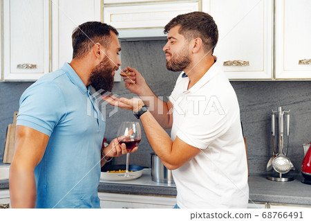 Happy homosexual couple preparing food together in kitchen Happy homosexual couple preparing food together in kitchen 68766491