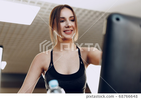 Pretty fit woman in black sportrswear training on a treadmill Pretty fit woman in black sportrswear training on a treadmill 68766648