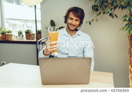 Bearded man using his laptop while drinking glass of beer 68766869