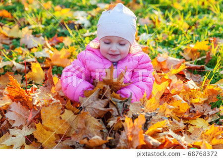 Happy young girl playing under falling yellow Happy young girl playing under falling yellow 68768372