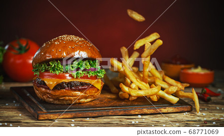 French fries fall next to cheeseburger, lying on 68771069