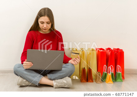 Young woman doing online shopping at home using 68771147