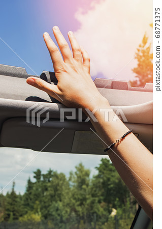 Feminine hand out from open hatch of a vehicle on sunny day. 68771375