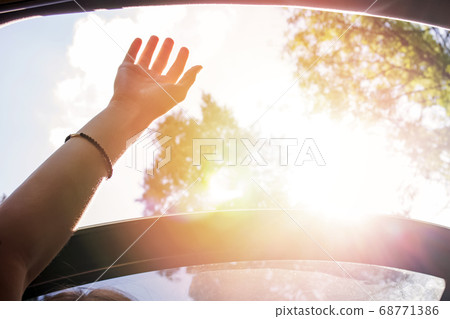 Feminine hand out from open hatch of a vehicle on sunny day. Feminine hand out from open hatch of a vehicle on sunny day. 68771386