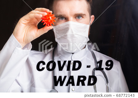 Covid-19 ward, Vaccine development and medicine concept - Doctor in flu mask holding a model of coronavirus. Covid-19 ward, Vaccine development and medicine concept - Doctor in flu mask holding a model of coronavirus. 68772143