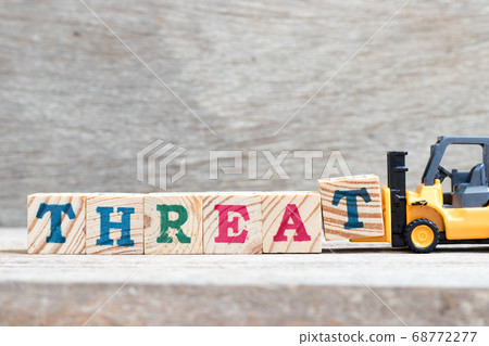 Toy forklift hold letter block t to complete word threat on wood background Toy forklift hold letter block t to complete word threat on wood background 68772277