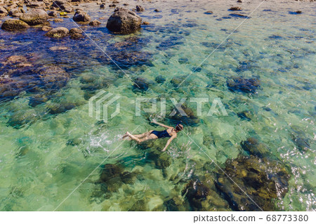 The woman is snorkeling among the corals. View from the drone The woman is snorkeling among the corals. View from the drone 68773380