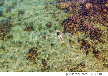The woman is snorkeling among the corals. View from the drone The woman is snorkeling among the corals. View from the drone 68774830
