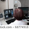 Professional Scientists Work in the Brain Research Laboratory. Neurologists Neuroscientists Surrounded by Monitors Showing CT, MRI Scans Having Discussions and Working on Personal Computers. 68774918